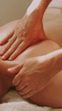close-up motion shows therapist hands gliding and kneading relaxing massage on oiled male back in spa light