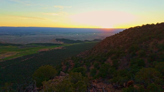 Warm evening sunlight illuminates lush farmland valleys and distant mountain ranges from Warner Point trail in Colorado