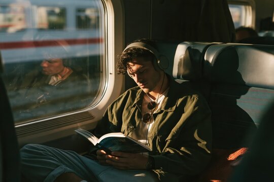 Man relaxing reading book on train journey