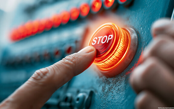 Hand pressing red stop button on control panel