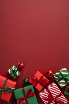 Merry Christmas and Happy New Year concept with wrapped red and green gifts and ornaments on red vertical background
