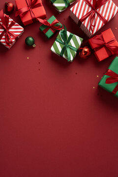 Merry Christmas and happy New Year with wrapped presents and ornaments on vertical burgundy red background