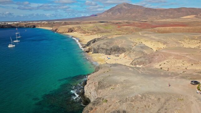 Drone view of Playa de Papagayo beach in Lanzarote. Clear turquoise water, golden sand and volcanic hills create a peaceful Atlantic island paradise.