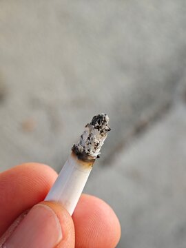 Close Up of Hand Holding Lit Cigarette with Burning Ash