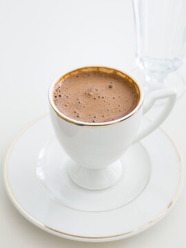 Traditional Turkish Coffee in White Porcelain Cup with Water Glass on White Background