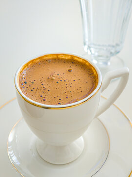 Close Up View of Foamy Turkish Coffee Served in White Gold Trim Cup