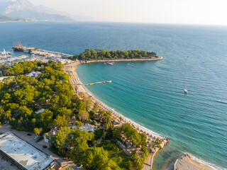 Obraz premium Aerial view of sandy beach, green pine forests, marina turquoise Mediterranean sea in Kemer, Antalya, Turkey Scenic coastal landscape with resort town, park and beautiful coastline under bright sun