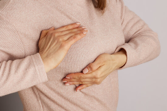 Close-up of a woman demonstrating the proper hand placement for a breast self-exam, focusing on prevention and womens health awareness.