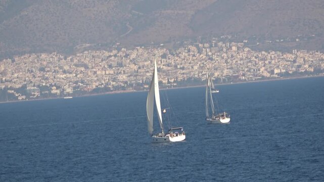 Two sailing yachts are heading for the land with open sails.