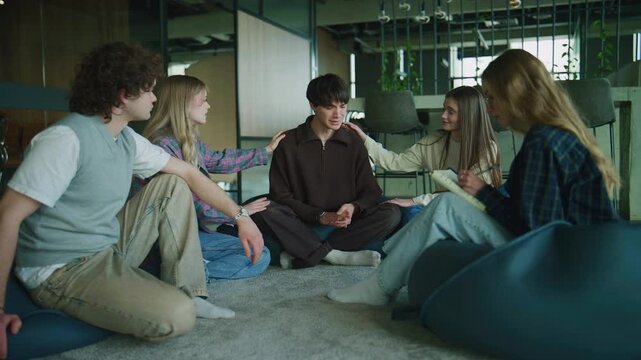Group engages in a psychology session focusing on support and communication. A guy is crying, and the others are supporting him.