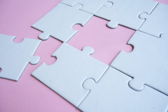 An incomplete puzzle with separate pieces. Puzzle arrangement against a pink background. Concept of finding solutions and problem-solving.