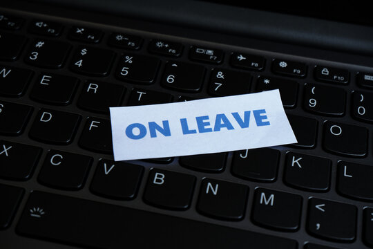 On leave, annual leave for an employee. An "ON LEAVE" sign sits above the keyboard, conveying the message at the workstation that the person is not currently working.