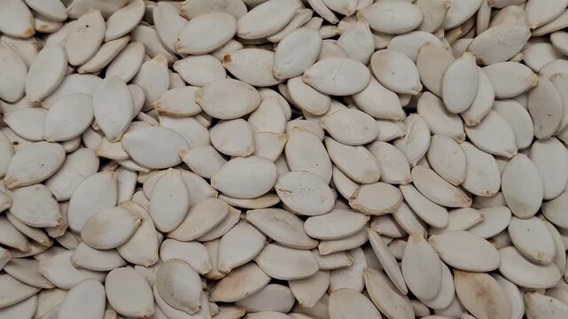 White pumpkin seeds filling the frame in close view. Natural snack, healthy food, raw ingredient, organic nutrition, texture background.