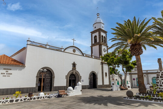 historic church in Arrecife, Lanzarote, surrounded by tall palm trees. The bright blue sky enhances the picturesque scene, capturing the essence of this charming location