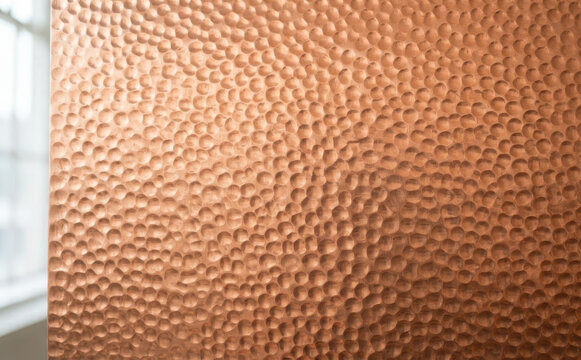 Hammered copper metal sheet texture background with a warm metallic brown surface for design