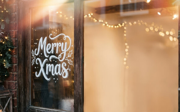 Merry Xmas window lettering on a cafe door with festive fairy lights during winter holidays