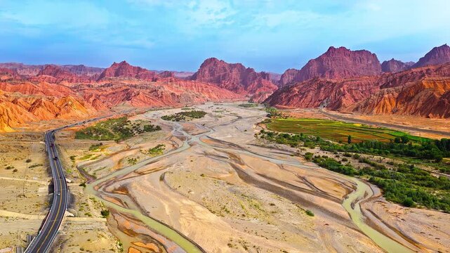 Aerial view of a winding riverbed and road traversing a dry canyon along the Duku Highway in Xinjiang, China