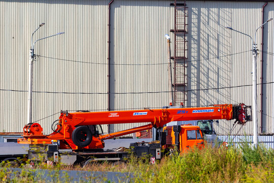 Powerful orange mobile crane parked at industrial construction site, heavy machinery ready for lifting operations during bright summer day: Russia - August 3, 2026