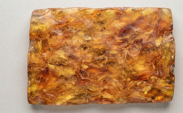 Polished block of natural amber gemstone with swirling golden brown patterns texture background for jewelry and design projects