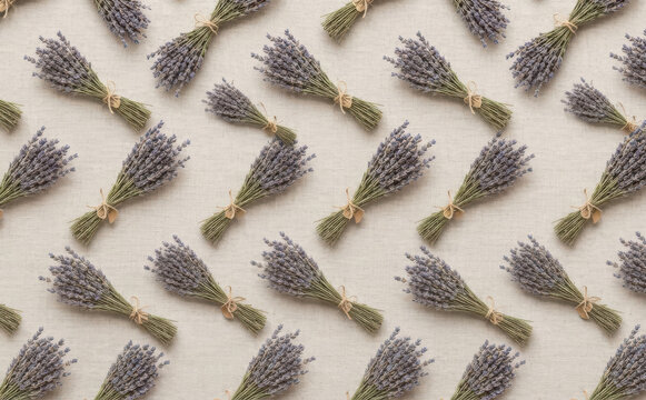 Aesthetic pattern of dry lavender flower bouquets arranged neatly on a neutral fabric background for natural wellness and relaxation design concepts