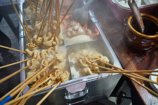 Steaming fish cake skewers simmer in a rich broth at an authentic Asian street food stall This comforting winter scene provides ideal visual context for regional culinary tourism and recipe media