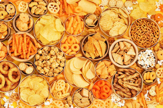 Colorful mix of salty snacks for beer varieties: potato and corn chips, popcorn and pretzels, rings and crackers. Non-healthy junk food background
