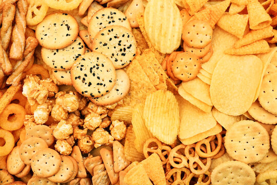 Colorful mix of salty snacks for beer varieties: potato and corn chips, popcorn and pretzels, rings and crackers. Non-healthy junk food background