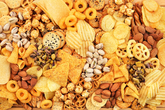 Colorful mix of salty snacks for beer varieties: potato and corn chips, popcorn and pretzels, rings and crackers. Non-healthy junk food background
