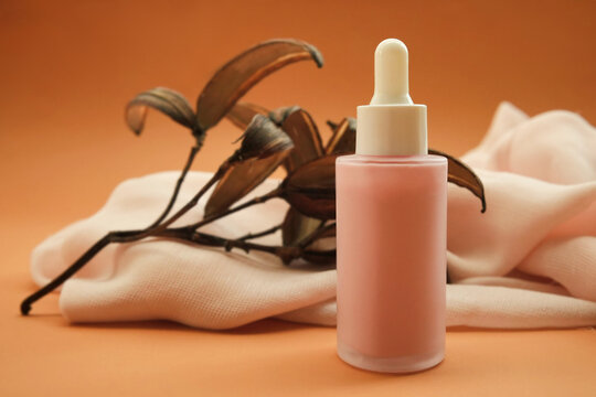Cosmetic serum bottle on delicate flowers background, natural  scincare cosmetics, beauty and facial care concept image, selective focus, shallow DOF