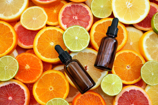 Cosmetic bottles on bright citrus fruits background, essential oil glass bottles, natural scincare cosmetics, beauty and facial care concept image, selective focus, shallow DOF