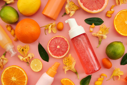 Cosmetic bottles on bright citrus fruits and flowers background, natural scincare cosmetics, beauty and facial care concept image, selective focus, shallow DOF