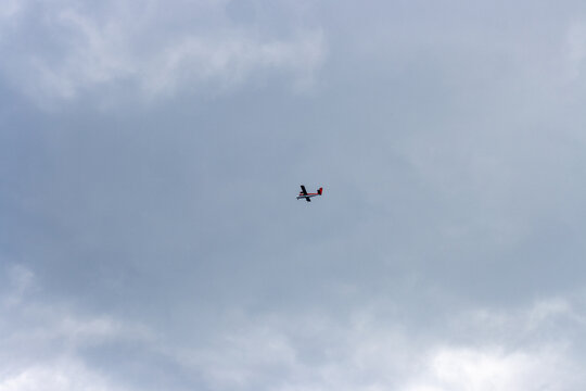 Quebec, Canada, 15 July 2026 : A small red and black airplane flies through a cloudy sky.