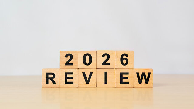 Wooden cube with 2026 review text, Concept of business review, new year planning, and annual reflection on gray background