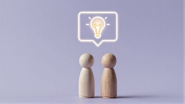 Two wooden figures face each other, sharing a glowing lightbulb idea.