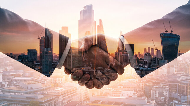 Professional business partners performing a firm handshake overlayed against a glowing golden modern city skyline background