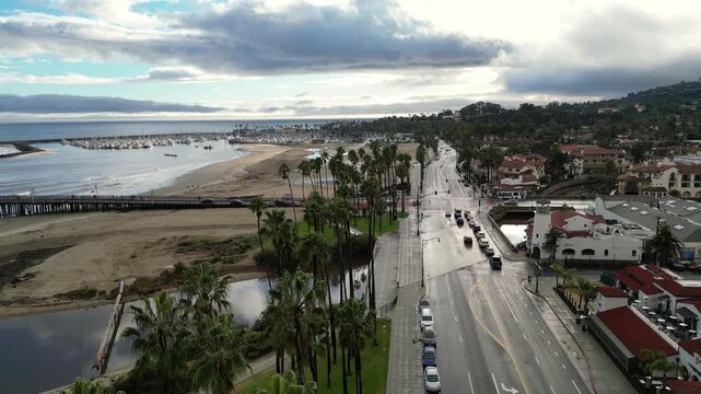 Aerial drone shot over Cabrillo Blvd. along the beach in Santa Barbara, California, passing State Street. Shot on a sunny afternoon after rain, January 2024.