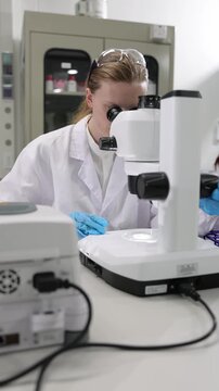Female scientist using a microscope in a research laboratory.