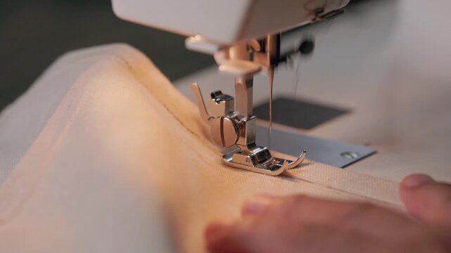 Close up of sewing machine needle and presser foot stitching linen fabric