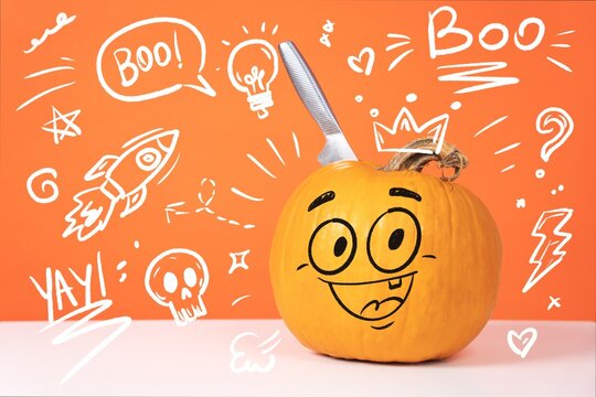 An orange pumpkin with a hand drawn smiling face and a knife stuck in its top stands on a white table against an orange background covered in playful doodles. A concept of quirky Halloween humor.