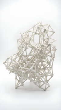 White lattice sculpture with geometric interconnected structure on plain backdrop