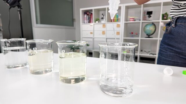 Pouring Clear Liquid Into Glass Beaker in Chemistry Laboratory