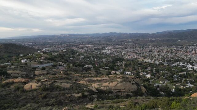 Panning right aerial view of Simi Valley, California from the Santa Susana Knolls neighborhood. Shot on a hazy, overcast January day in 2024.
