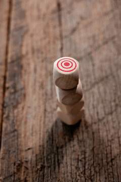 Stacked Wooden Figures with Target Symbol on Rustic Wooden Surface