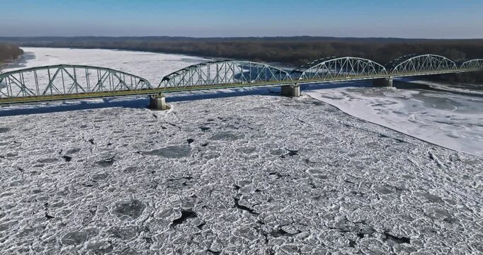 Metal bridge crossing over the frozen surface of Brda River.