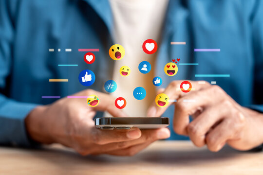 Social media network communication and online engagement reaction. Man hand holding smartphone using emoji emoticon heart like and message.