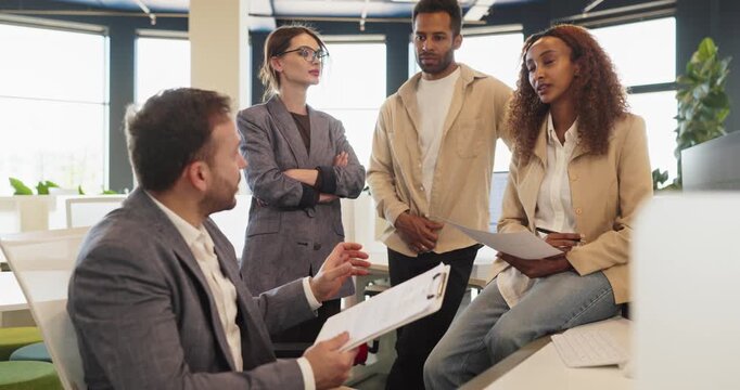 Business team in office meeting discussing collaboration. Colleagues review a report, share ideas, and align strategy around project goals during discussion. Teamwork and strategy concept shown.