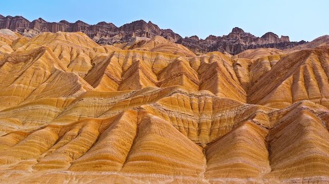 Aerial footage of rugged mountain slopes with colorful geological sandstone patterns in the Red Mountain Stone Forest, Kuqa, Xinjiang, China