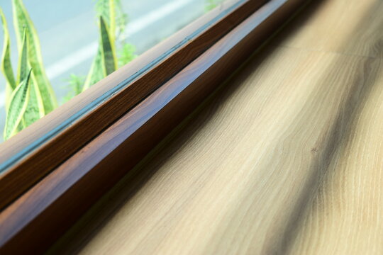 modern wooden window frame sill with green plant outside
