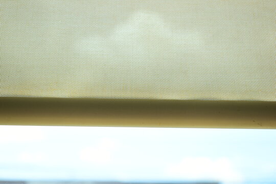 beige window roller shade bar with blue sky view