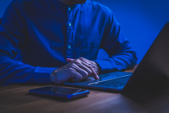 Close-up of freelance male hands typing on a laptop keyboard while working at a wooden desk, using internet technology for communication, remote work and digital nomad.